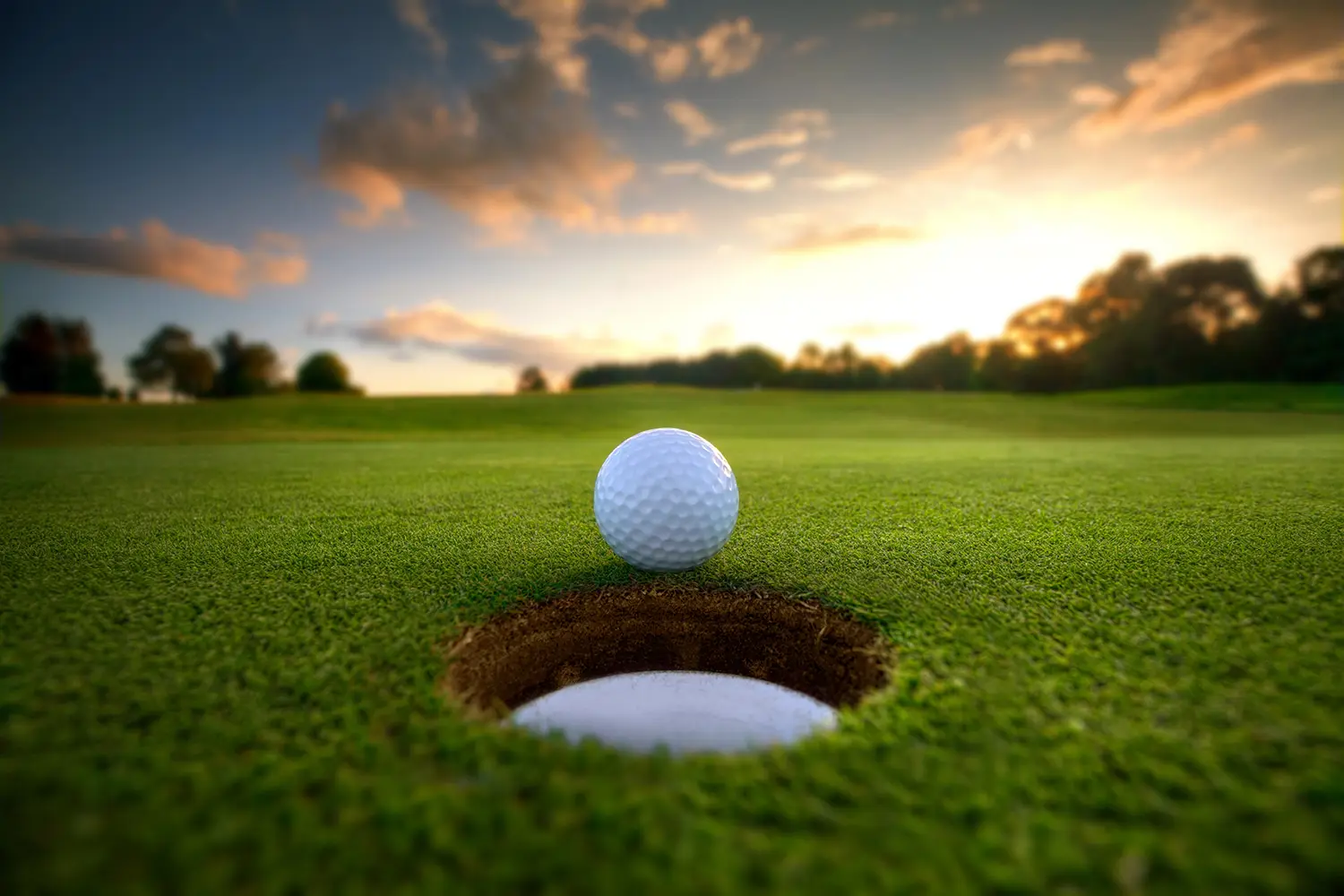 Golfbal bij een hole in het avondlicht